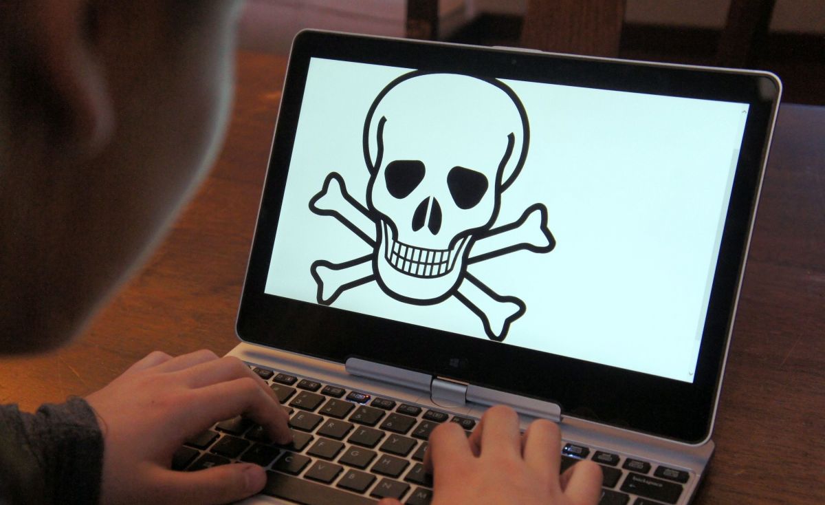 Child at laptop with skull and crossbones on screen