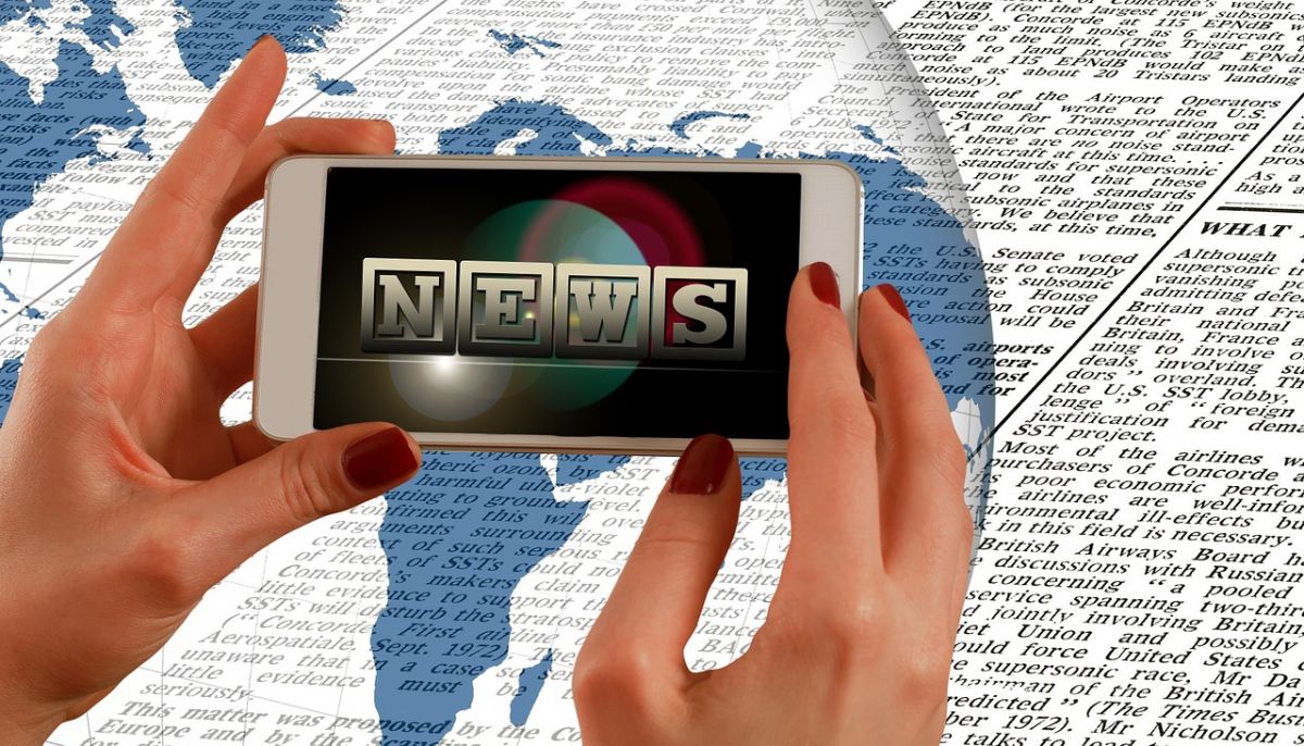 Hand holding a smartphone showing "news"