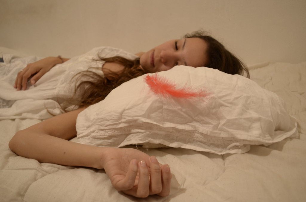 mujer dormida sobre una cama con almohadón de plumas rojas